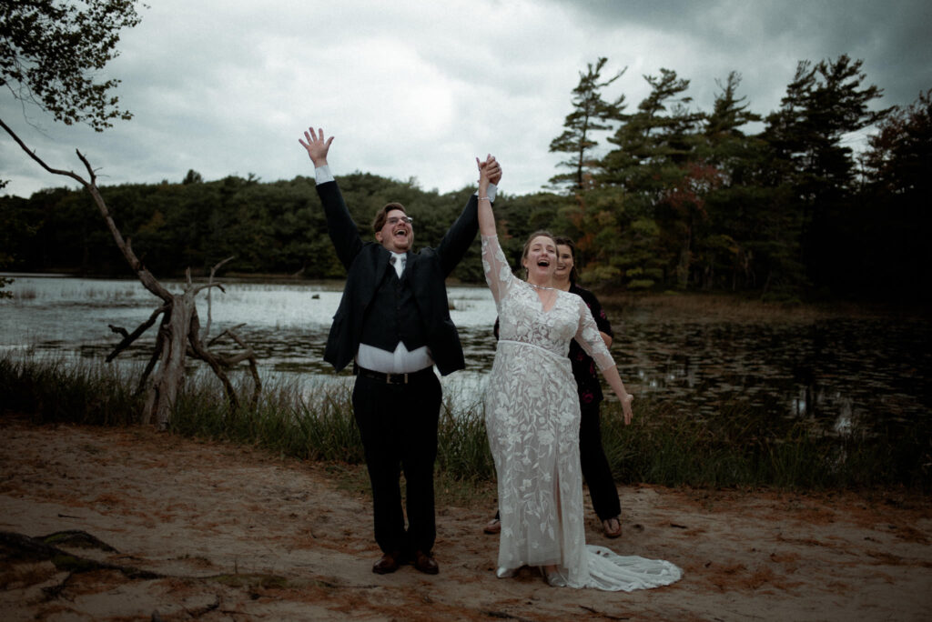 Bride and groom who just eloped raising their hands in joy.