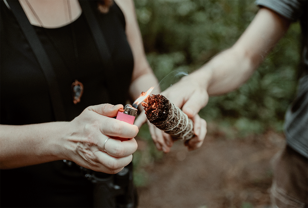 Lighting a sage smudge stick at an elopement ceremony.