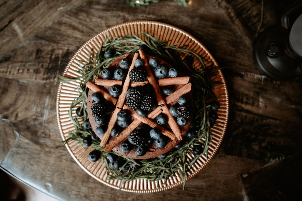 Wedding cake with a cinnamon stick pentagram and fresh blackberries.