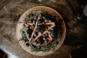 Wedding cake with a cinnamon stick pentagram and fresh blackberries.