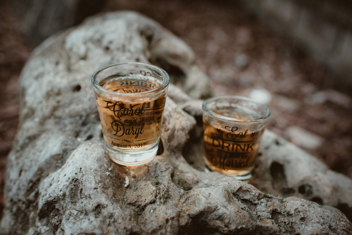 Custom wedding shot glasses on a rock.