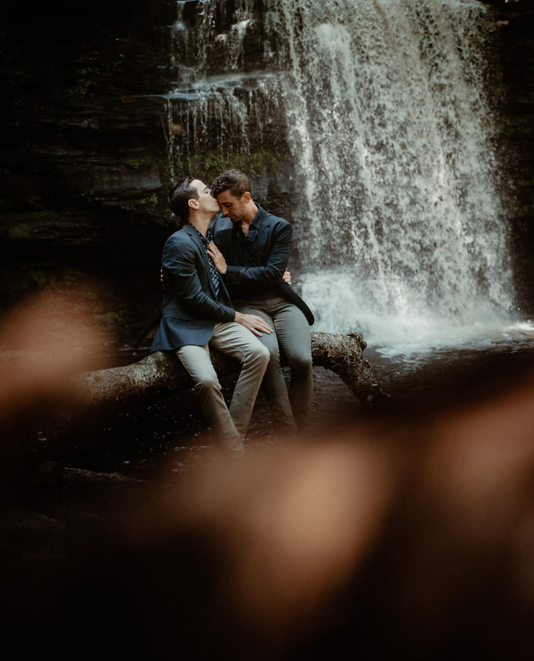 Gay couple portrait in front of a waterfall