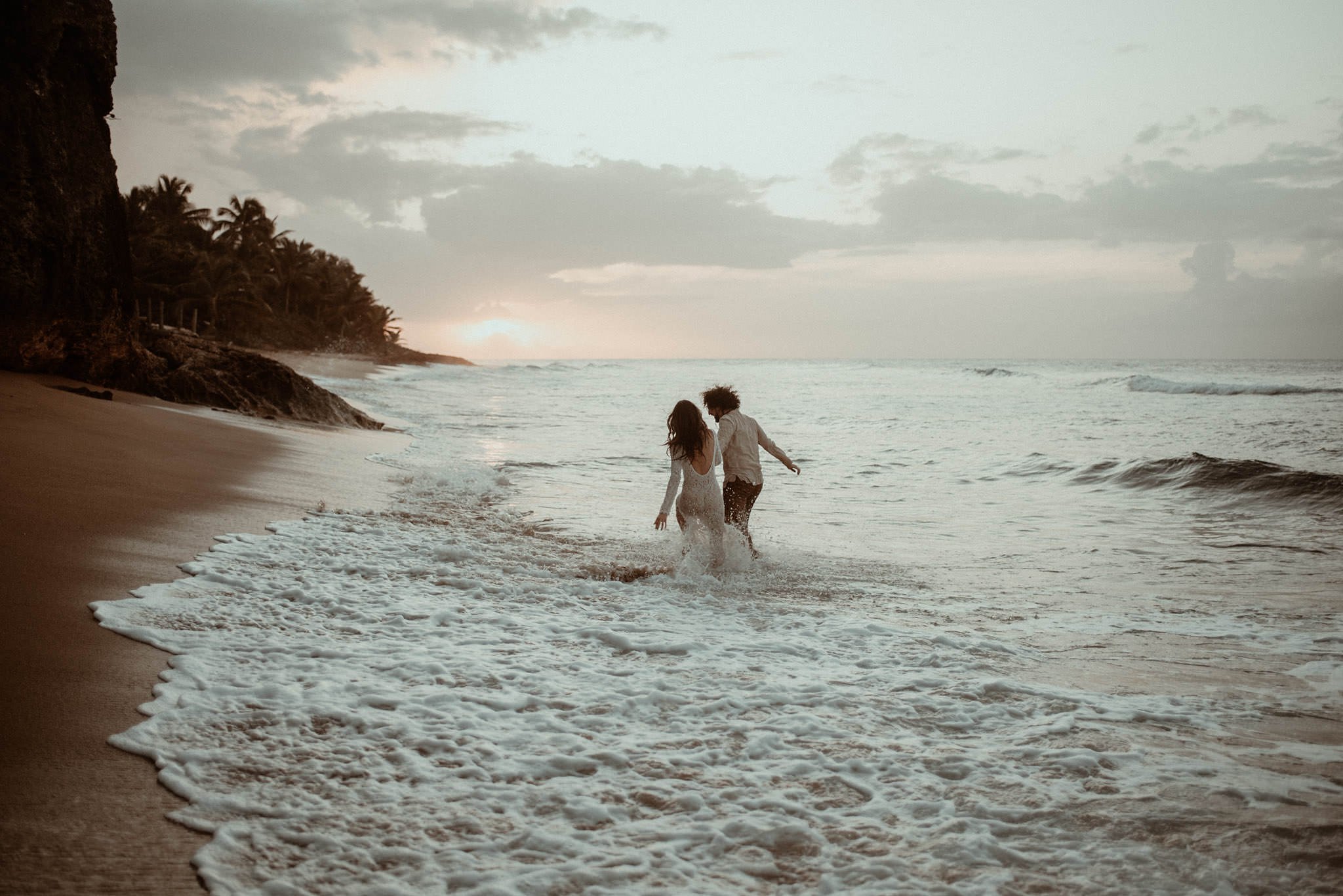 Couple running toward the sunset in the ocean