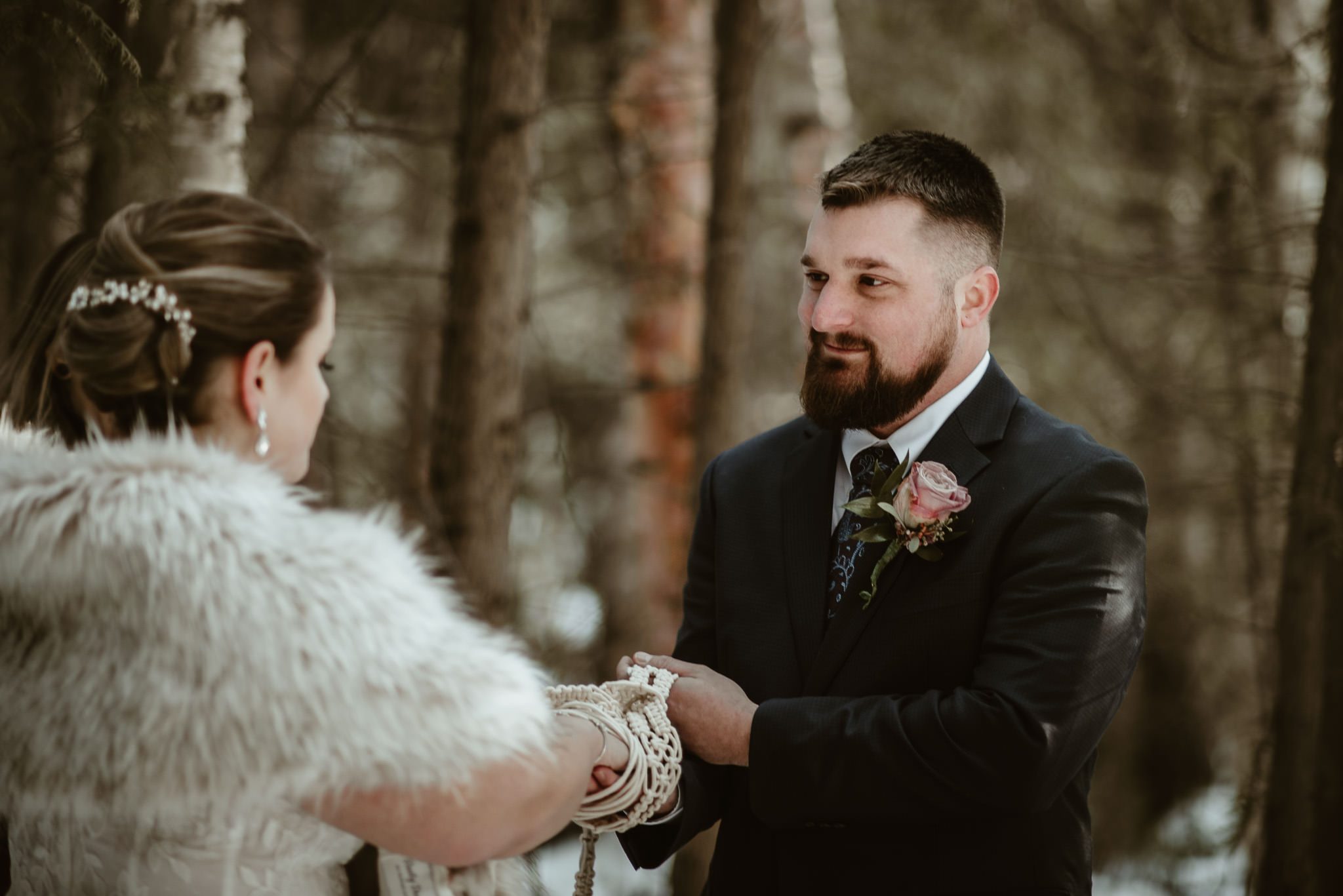 A bride and groom performing a handfasting ceremony at their winter elopement in Michigan.
