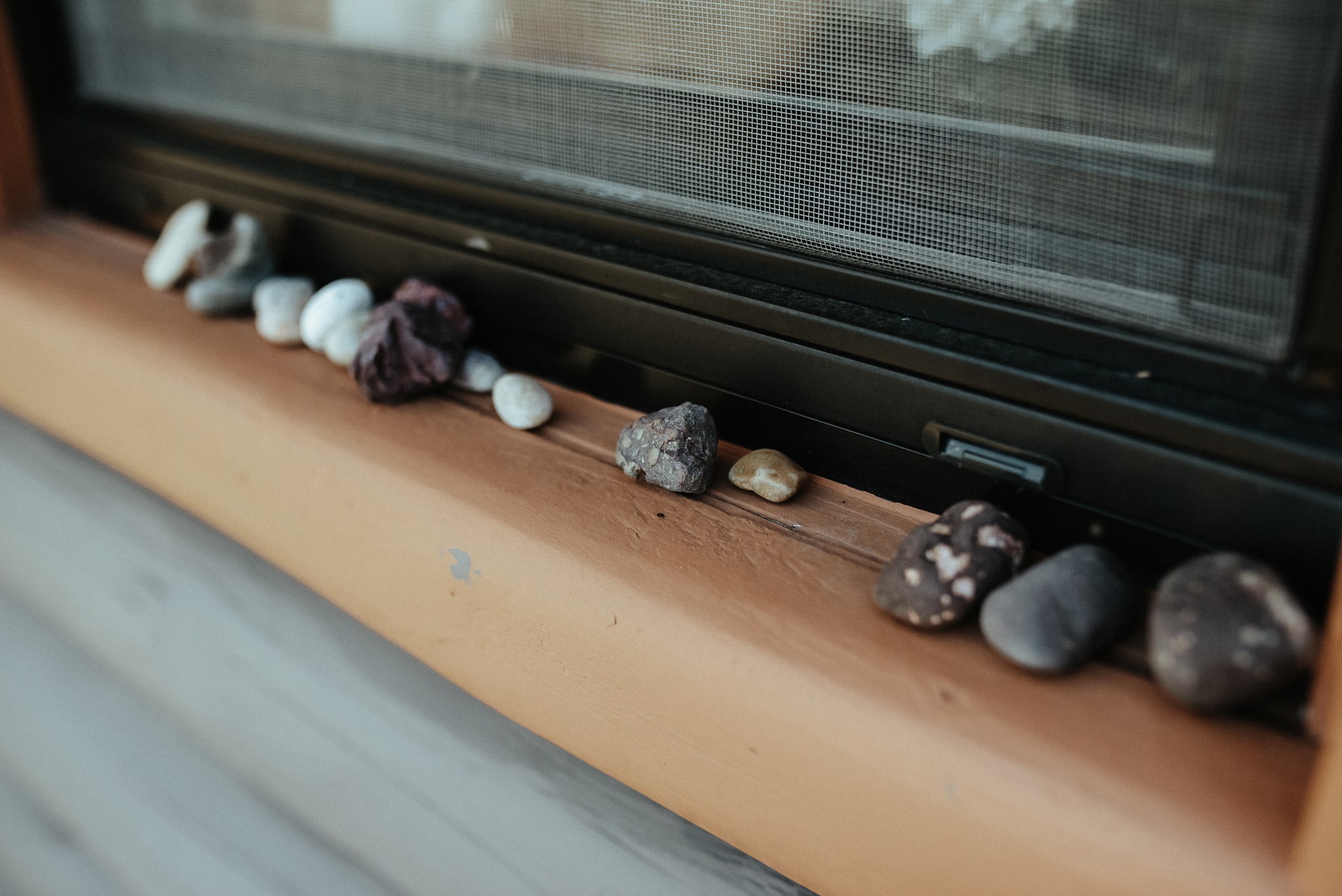 Lake Superior rocks lined up in a row on a cabin windowsill.