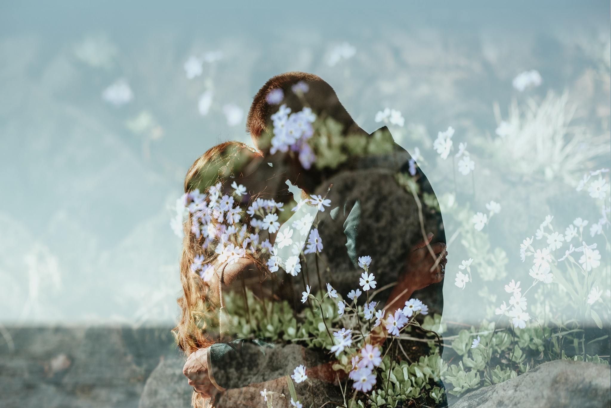 A double-exposure of the couple kissing with small purple flowers overlayed.