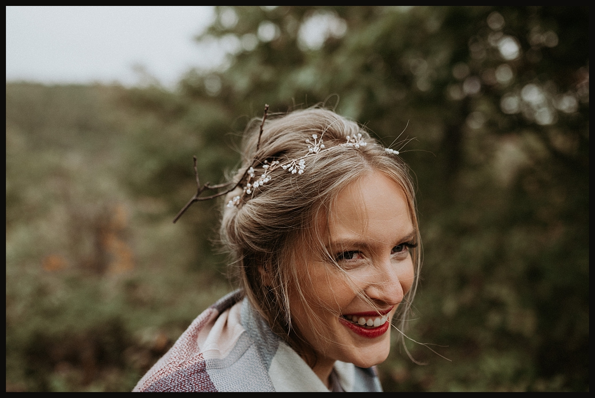 Bride with a twig stuck in her hair, smiling.