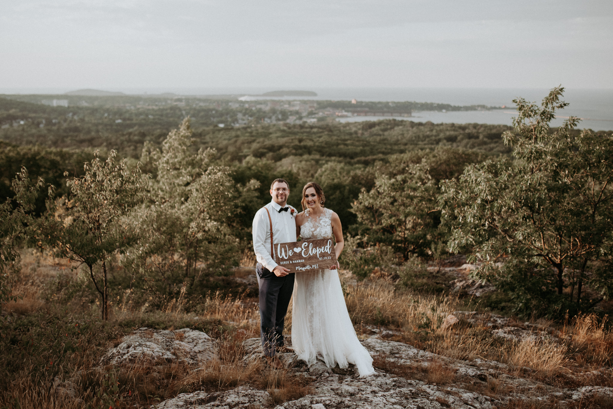 Bride and groom holding "We Eloped" sign on Marquette Mountain.