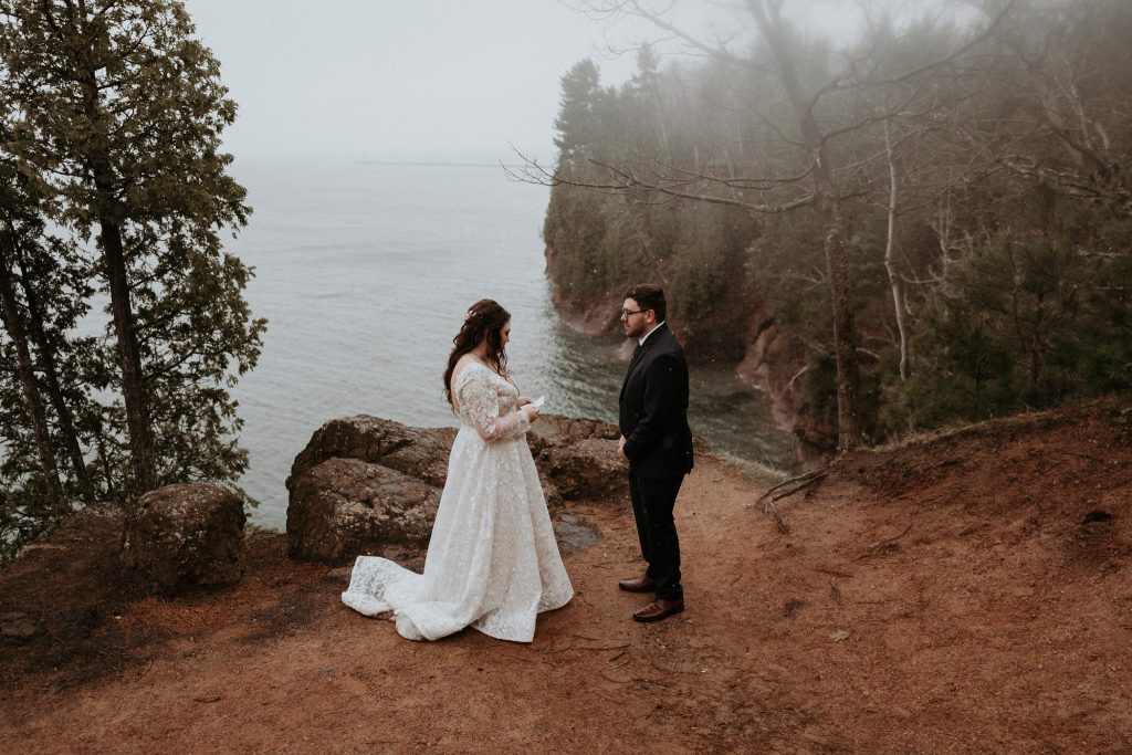 Couple reading wedding vows on a cliff above Lake Superior on Presque Isle, Marquette Michigan