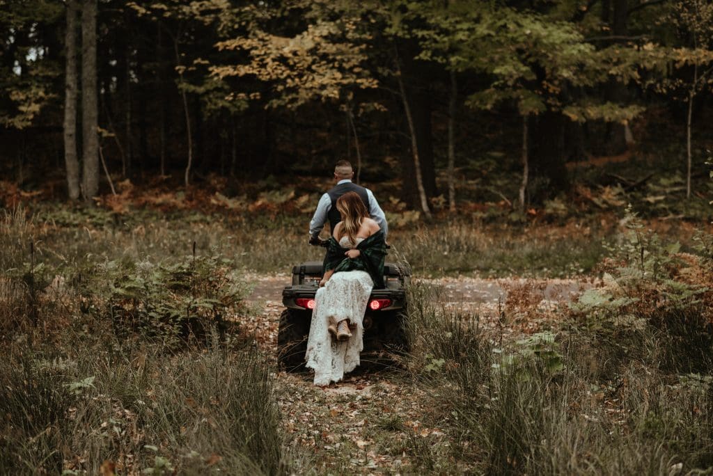 Bride and groom riding a four-wheeler ORV after their Michigan elopement.